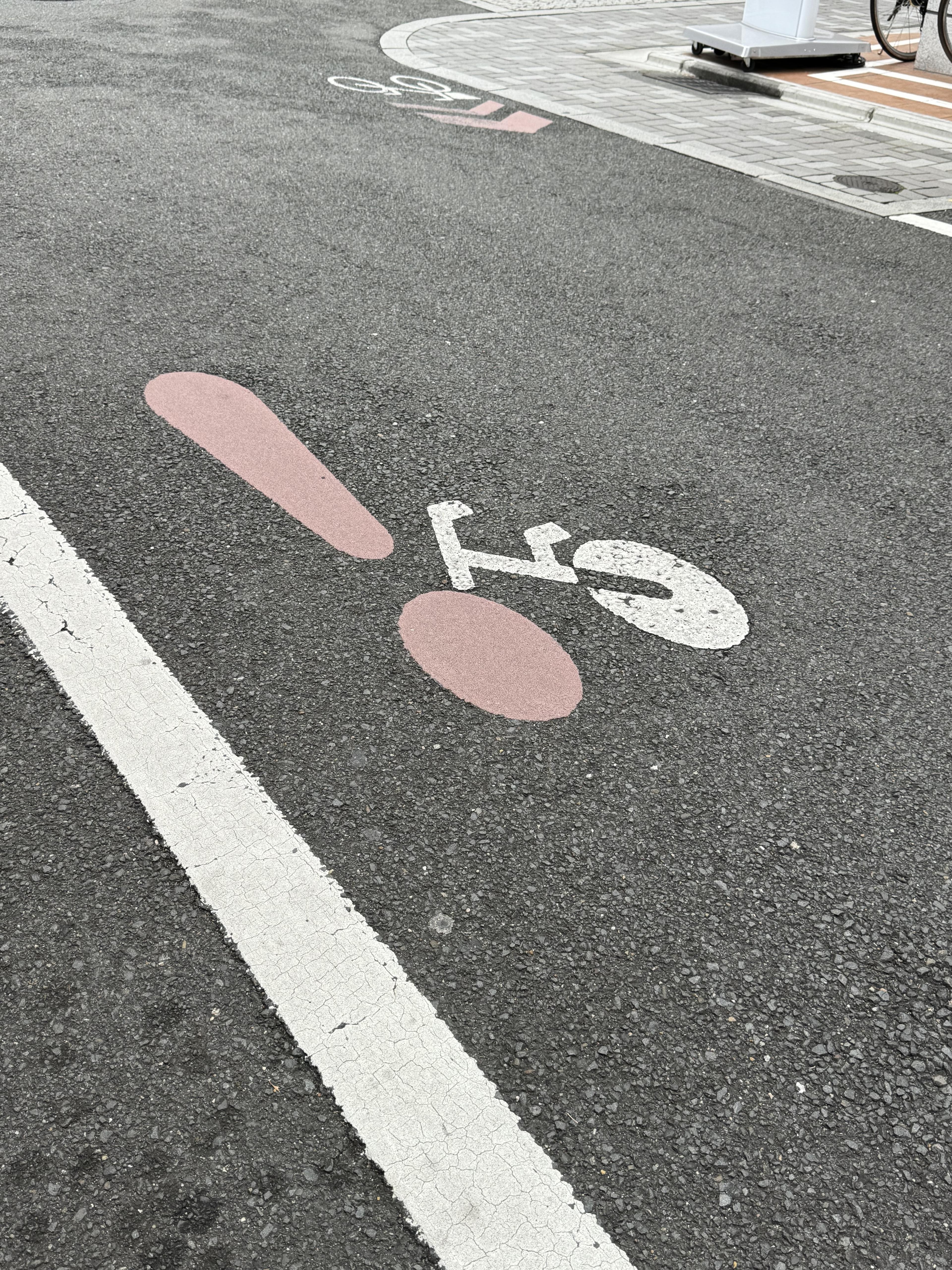 A sign on the bike path in Kyoto, combining an exclamation mark with the front wheel of an abstract bike