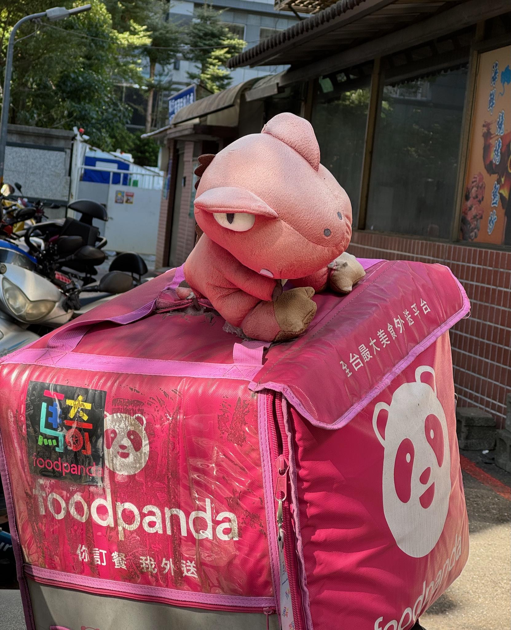 Foodpanda mascot plush on a delivery backpack on a scooter outside